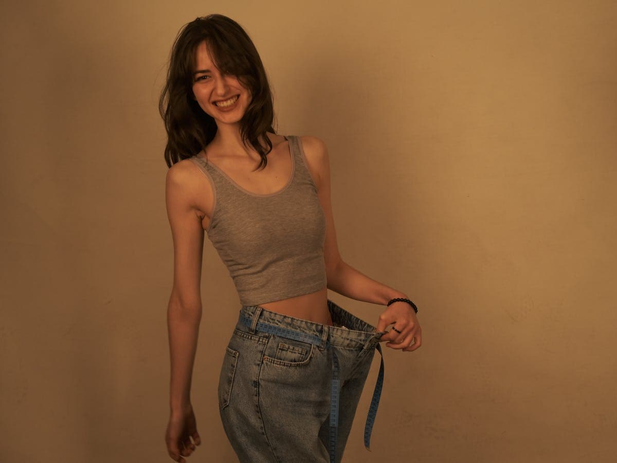Smiling woman showing her weight loss in loose-fitting jeans
